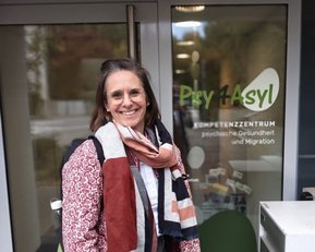 A woman with glasses and a scarf stands in front of the entrance to the Psychiatry and Migration Center 'Psy 4 Asylum.
