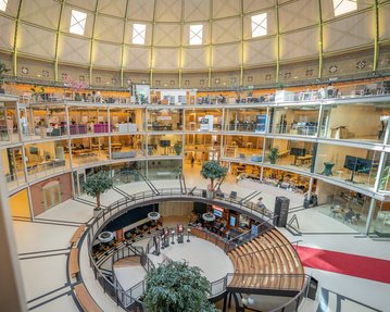Interior view of a modern multi-story building featuring round balconies, plants, and seating areas in the center.