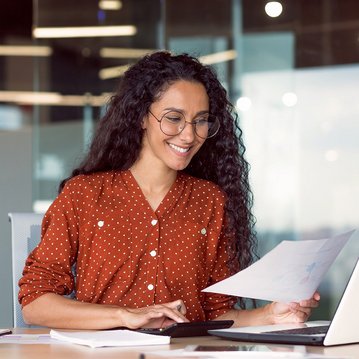 Hispanic-looking businesswoman working on her laptop and smiling.