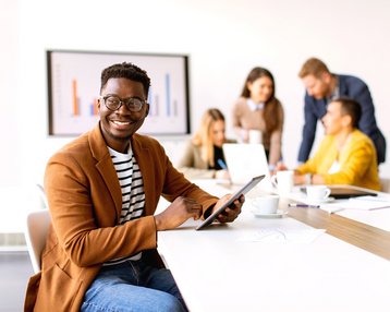 Young African American businessman working on his tablet in front of his colleagues in the boardroom.